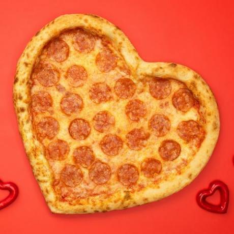 pepperoni de pizza en forma de corazón para el día de san valentín sobre fondo de papel rojo