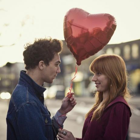 pareja con hombre sosteniendo globo en forma de corazón rojo