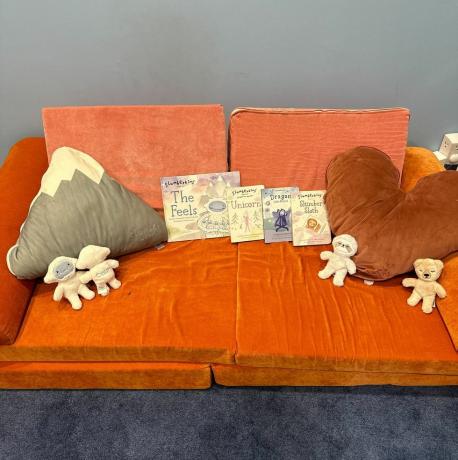 buena revisión de limpieza de slumberkins una colección de peluches, libros y almohadas de slumberkins en un sofá naranja