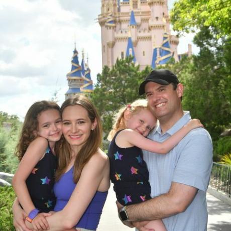 una familia sonriendo frente al castillo de cenicienta en el parque magic kingdom