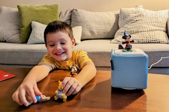 un niño sentado en una mesa jugando con figuritas de juguete escuchando un toniebox jugando con tonies mickey mouse winnie the pooh peter conejo