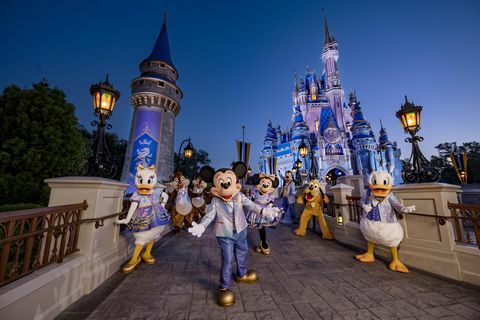 mickey mouse y sus amigos luciendo sus brillantes modas del 50 aniversario mientras posan frente al castillo de cenicienta en el parque magic kingdom