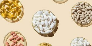 varias pastillas y cápsulas, vitaminas y suplementos dietéticos en placas de petri sobre fondo beige