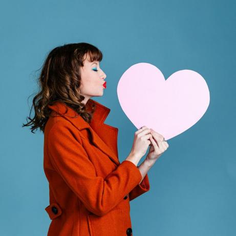 mujer joven con corazón de papel rosa