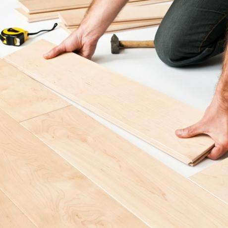 Cerca del hombre poniendo tablas de suelo de paneles de madera